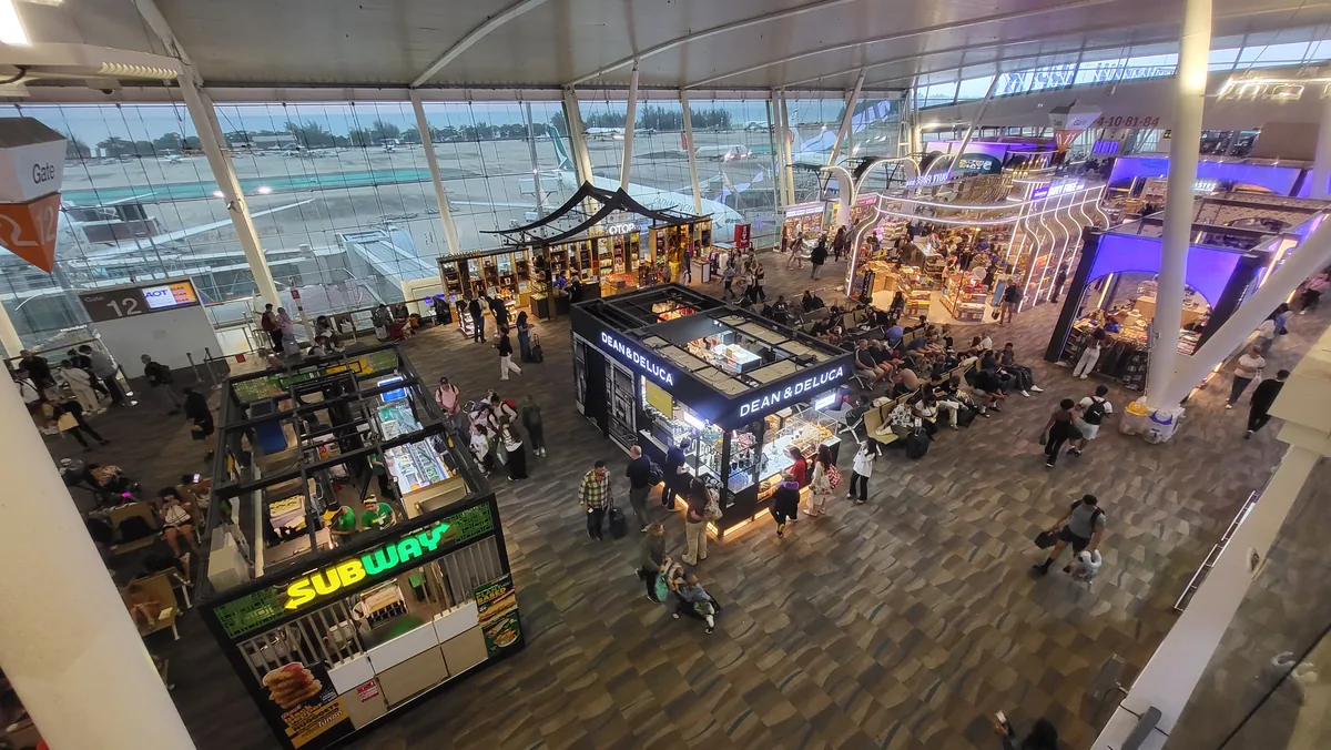 Shops and seating beneath high windows in a Phuket Airport departure hall