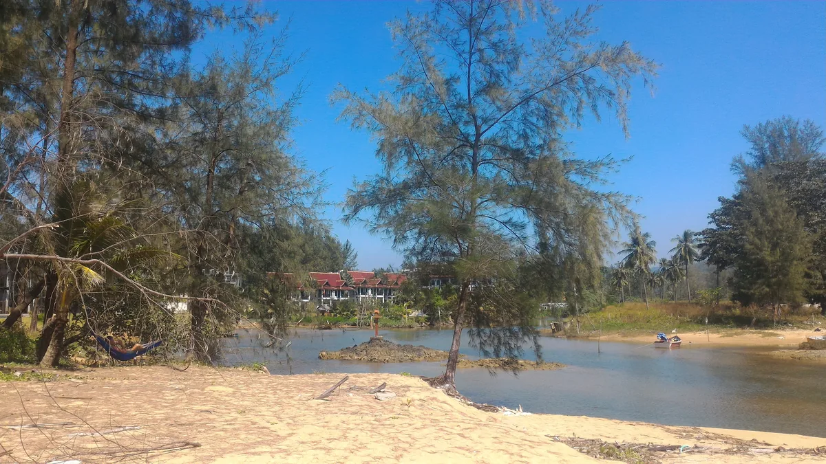 Calm water at the Khlong Bang Niang estuary with trees along the opposite bank