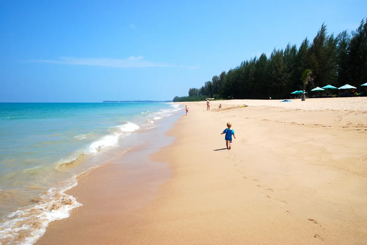Blue water and wide sand at Khuk Khak Beach, with distant walkers