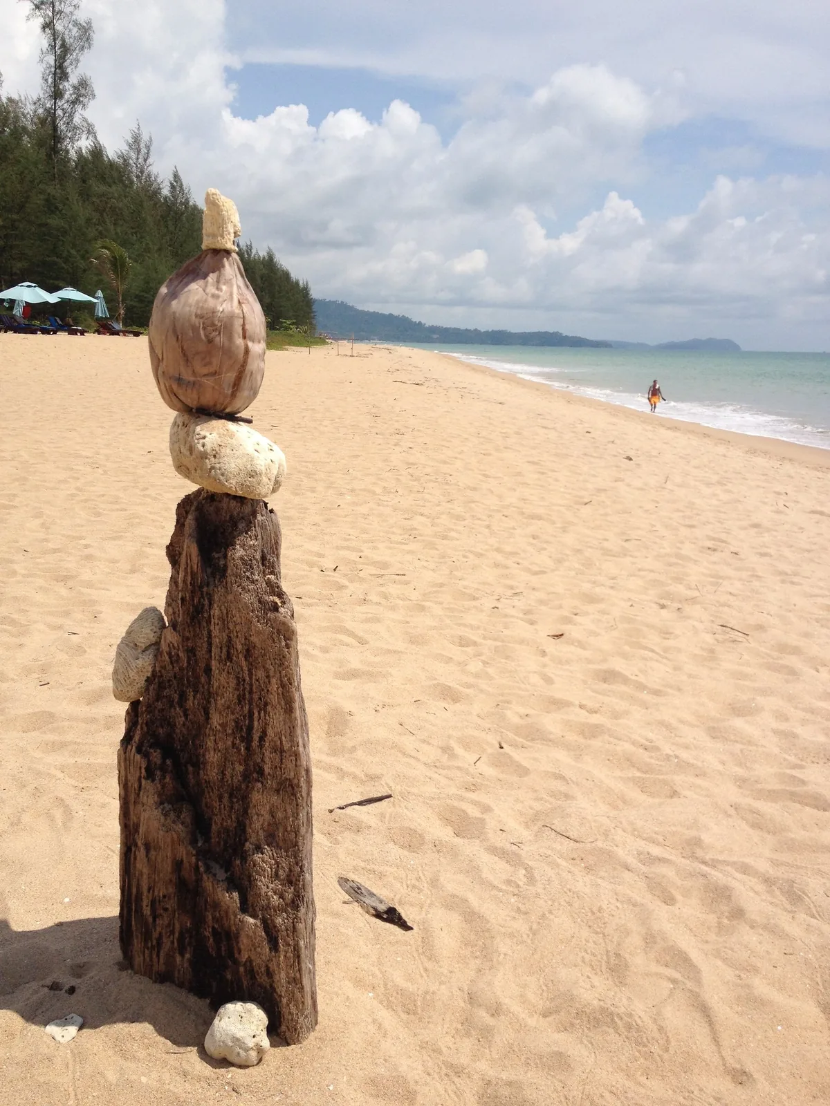 A piece of driftwood topped with stones beside Khuk Khak Beach