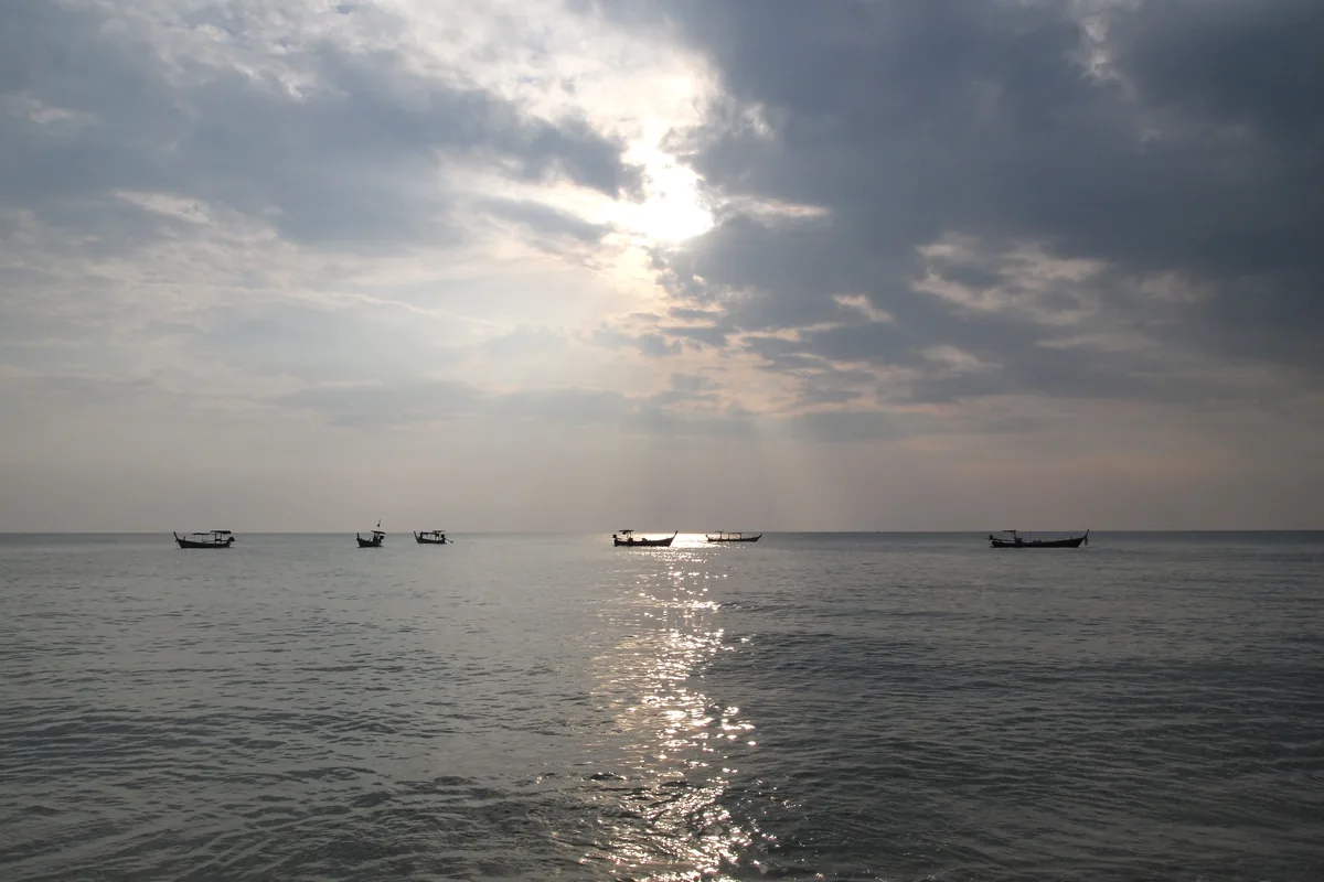 Andaman Sea coastline and boats beneath a glowing sky in Khao Lak–Lam Ru National Park