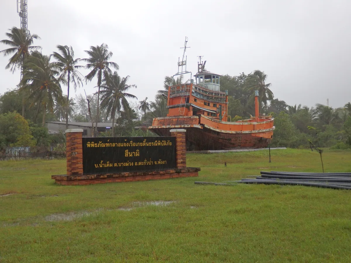 Preserved red fishing boat on land at Ban Nam Khem